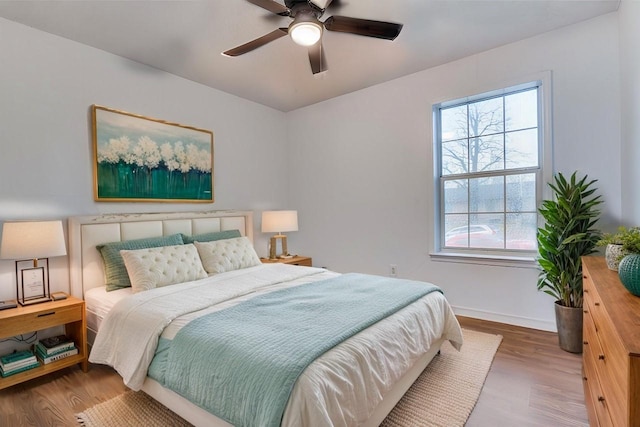 bedroom featuring wood finished floors, baseboards, and ceiling fan