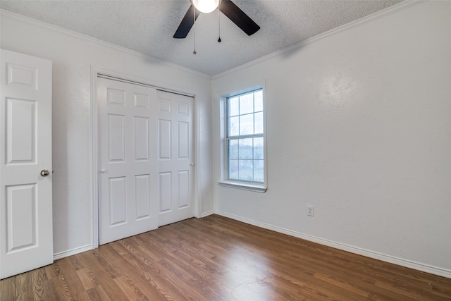 unfurnished bedroom with wood finished floors, baseboards, ornamental molding, a closet, and a textured ceiling