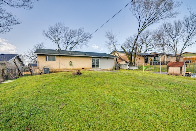 rear view of property featuring brick siding, a lawn, cooling unit, and fence