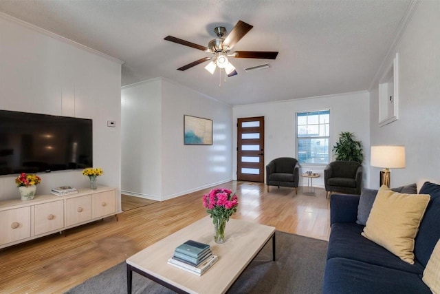 living room with light wood-type flooring, a ceiling fan, visible vents, and crown molding