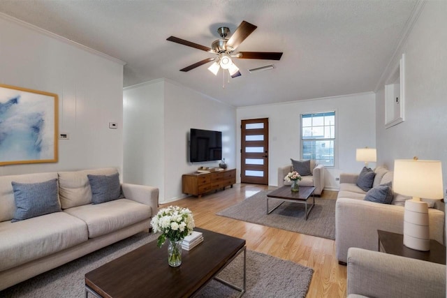 living room featuring visible vents, light wood-style flooring, a ceiling fan, and ornamental molding