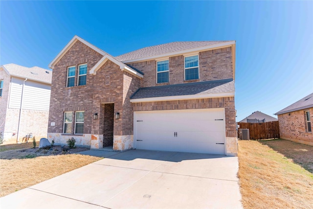 traditional-style home featuring driveway, a shingled roof, an attached garage, fence, and central air condition unit