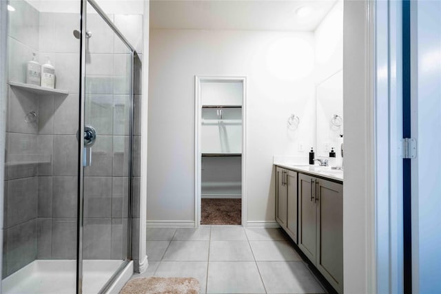 bathroom with tile patterned floors, a shower stall, a spacious closet, and vanity