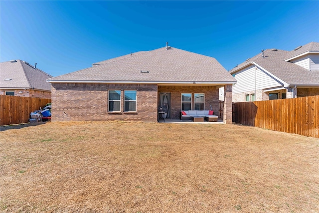 rear view of property featuring a yard, a fenced backyard, and brick siding