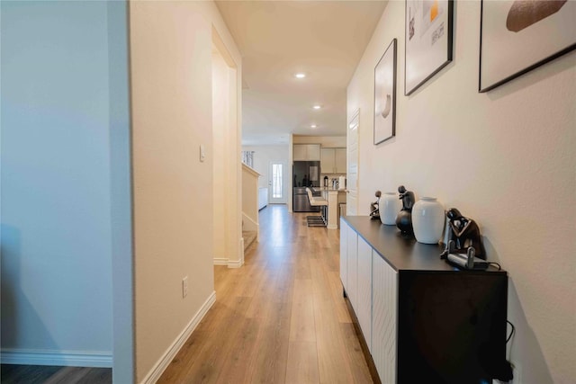 corridor with light wood-type flooring, recessed lighting, baseboards, and stairs