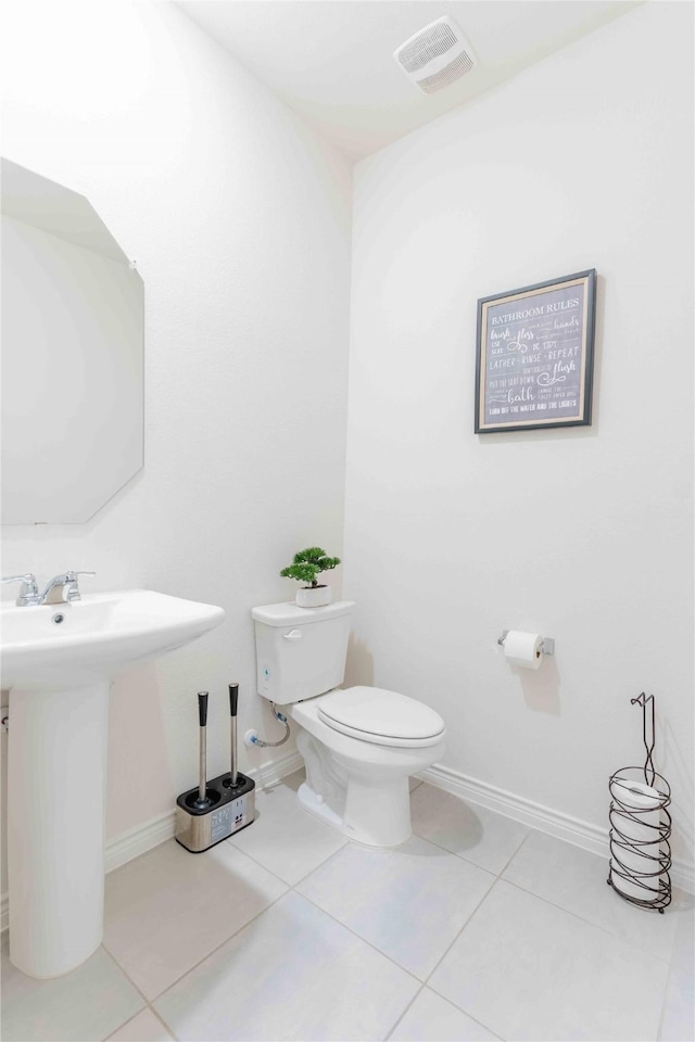 half bathroom featuring tile patterned flooring, baseboards, visible vents, and toilet