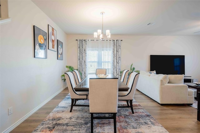 dining area featuring a chandelier, wood finished floors, visible vents, and baseboards