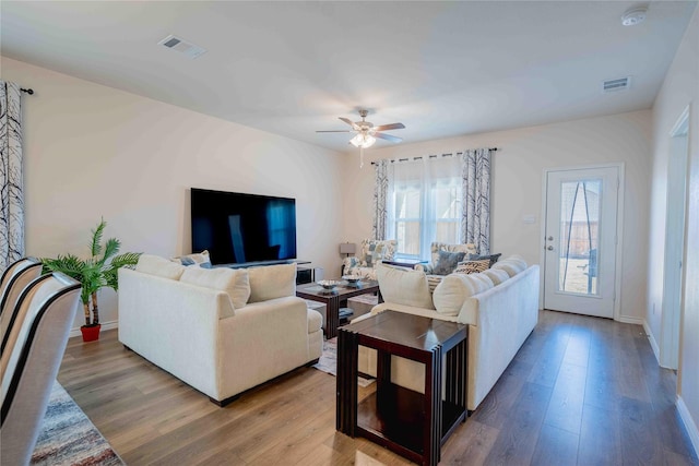 living room with wood finished floors, visible vents, and a healthy amount of sunlight