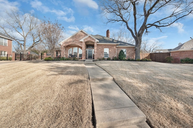 view of front facade with brick siding, fence, and a chimney