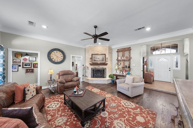 living area with a fireplace, visible vents, wood finished floors, and ornamental molding