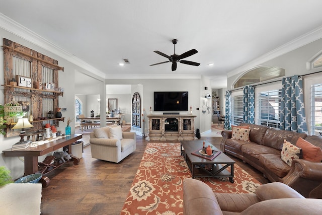 living room featuring ornamental molding, a ceiling fan, visible vents, and wood finished floors