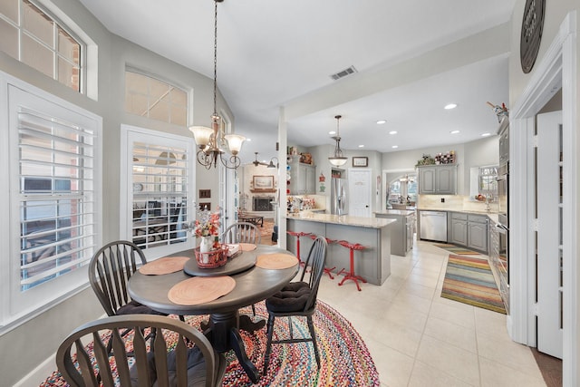 dining area with light tile patterned flooring, recessed lighting, visible vents, and an inviting chandelier