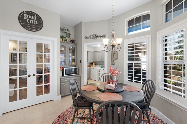 dining space featuring light tile patterned floors, french doors, an inviting chandelier, and washing machine and clothes dryer