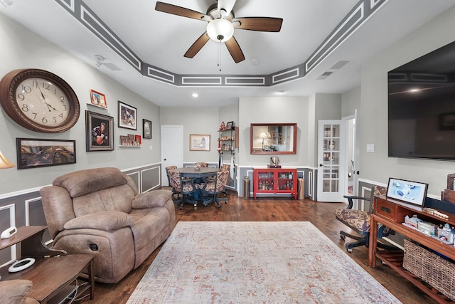 living room with visible vents, a tray ceiling, dark wood finished floors, and a ceiling fan