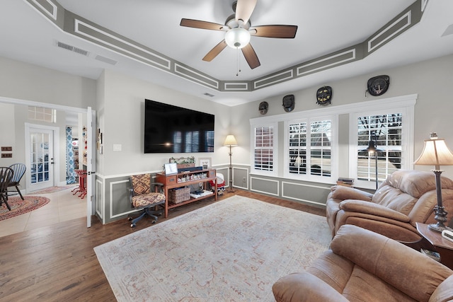 living room featuring visible vents, a ceiling fan, a raised ceiling, and wood finished floors