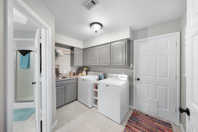 clothes washing area featuring cabinet space, visible vents, a sink, and independent washer and dryer