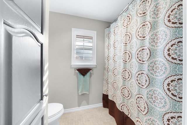 bathroom with a shower with curtain, toilet, and baseboards