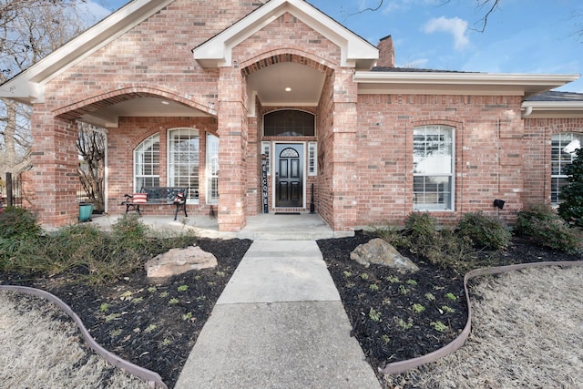 entrance to property with brick siding and a chimney