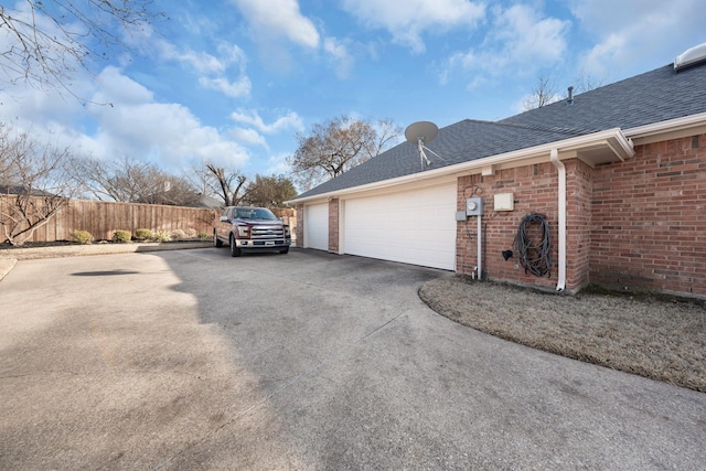 view of property exterior featuring driveway, a shingled roof, fence, and brick siding