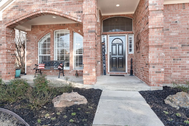 entrance to property with covered porch and brick siding