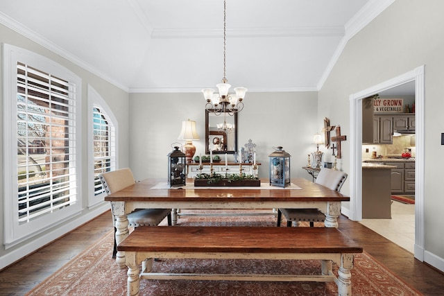 dining space with baseboards, crown molding, a chandelier, and wood finished floors