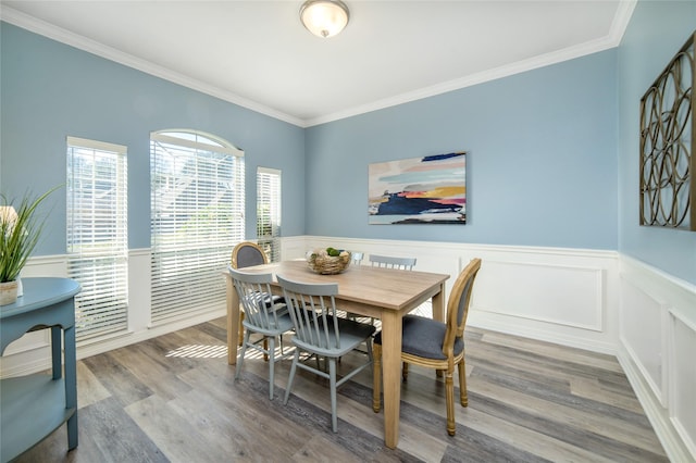 dining area featuring wainscoting, crown molding, and wood finished floors