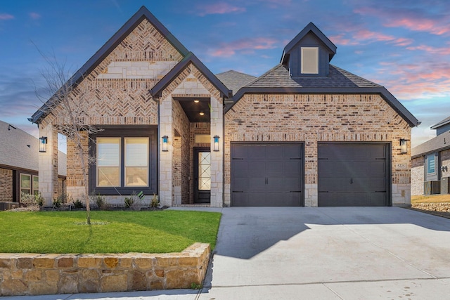 french provincial home with an attached garage, stone siding, concrete driveway, and brick siding