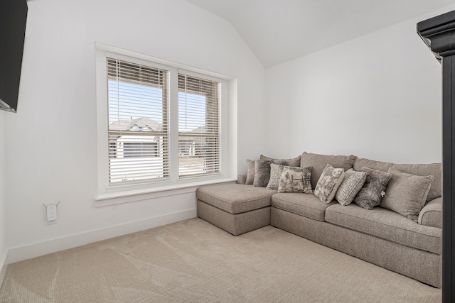 carpeted living area with lofted ceiling and baseboards