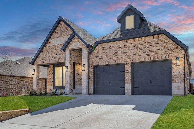 french country home featuring a garage, concrete driveway, brick siding, and stone siding