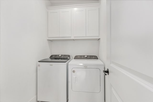 clothes washing area featuring washer and clothes dryer and cabinet space