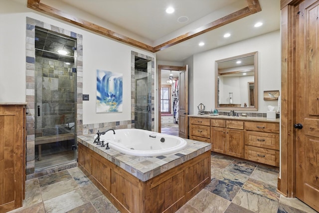 full bathroom featuring vanity, stone tile floors, a tub with jets, and a stall shower