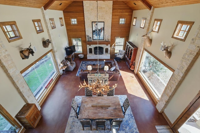 living area with high vaulted ceiling, wood walls, wood ceiling, and a large fireplace