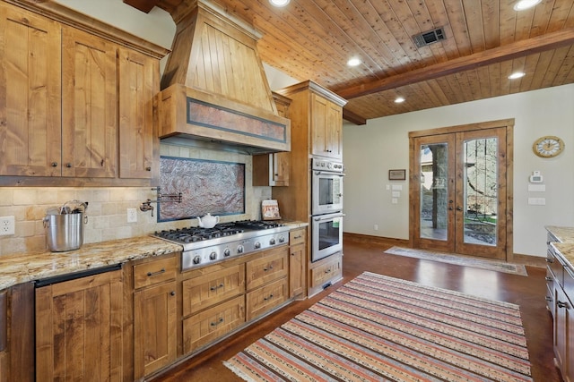 kitchen with visible vents, premium range hood, beam ceiling, decorative backsplash, and stainless steel appliances