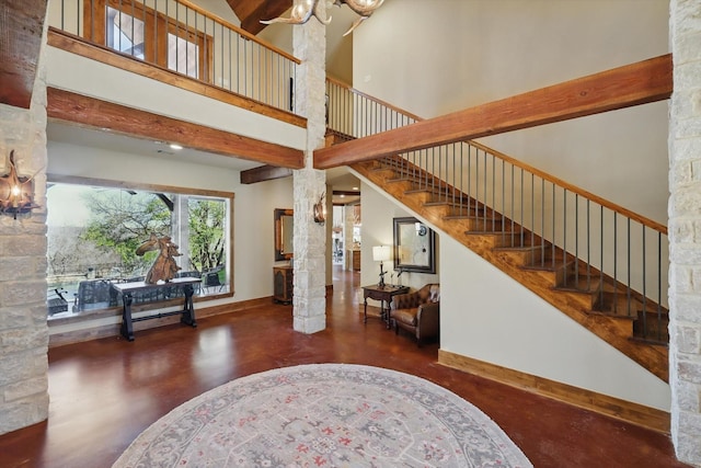 foyer with finished concrete floors, a high ceiling, baseboards, a chandelier, and stairs