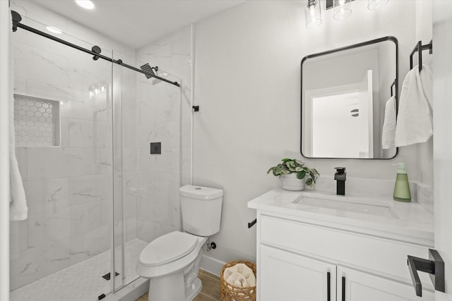 bathroom featuring a marble finish shower, baseboards, vanity, and toilet