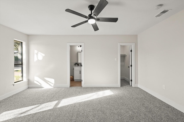 unfurnished bedroom with baseboards, visible vents, a walk in closet, and carpet flooring