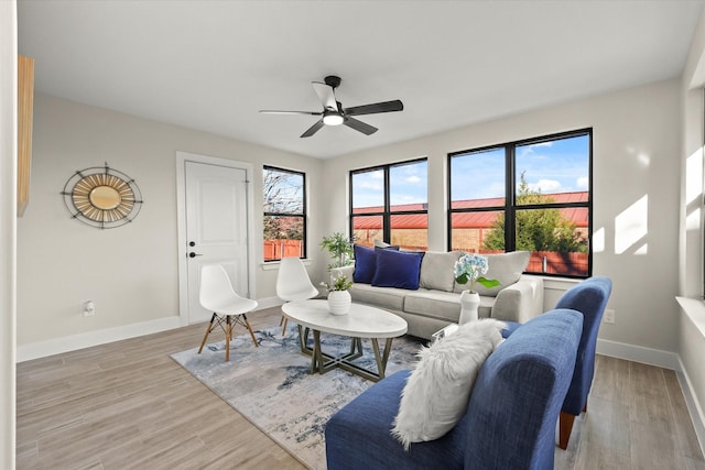 living area featuring light wood-type flooring, ceiling fan, and baseboards