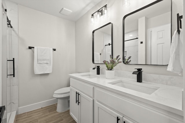 full bathroom with wood finished floors, a stall shower, a sink, and toilet