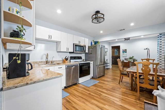 kitchen featuring visible vents, light wood-style flooring, a sink, stainless steel appliances, and white cabinets