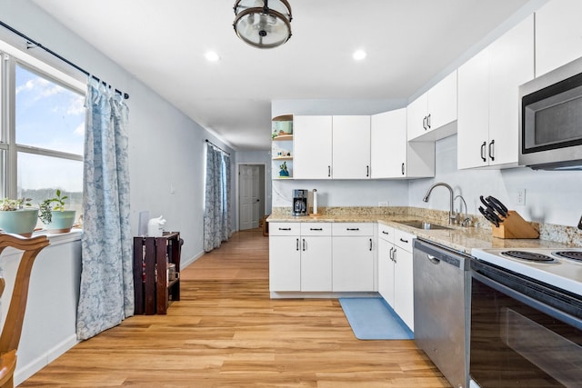 kitchen with a sink, open shelves, white cabinetry, stainless steel appliances, and light wood-style floors