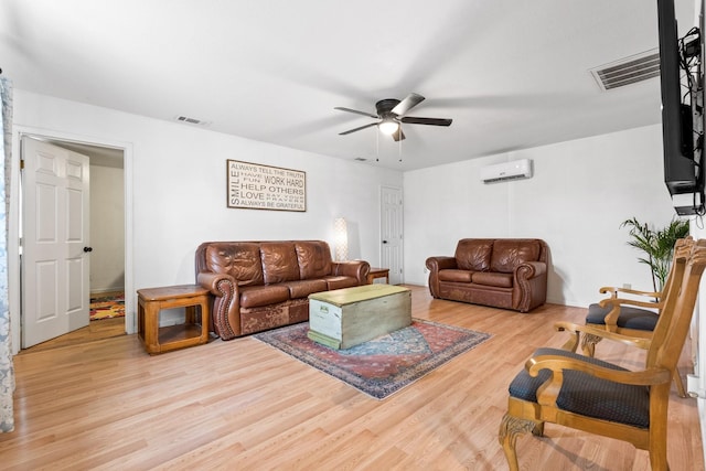 living room with ceiling fan, visible vents, wood finished floors, and a wall unit AC