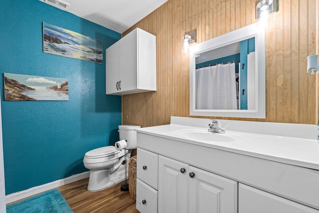 full bath featuring visible vents, toilet, wood finished floors, a textured wall, and vanity