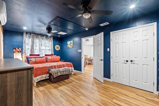 bedroom featuring visible vents, a textured ceiling, attic access, and light wood finished floors