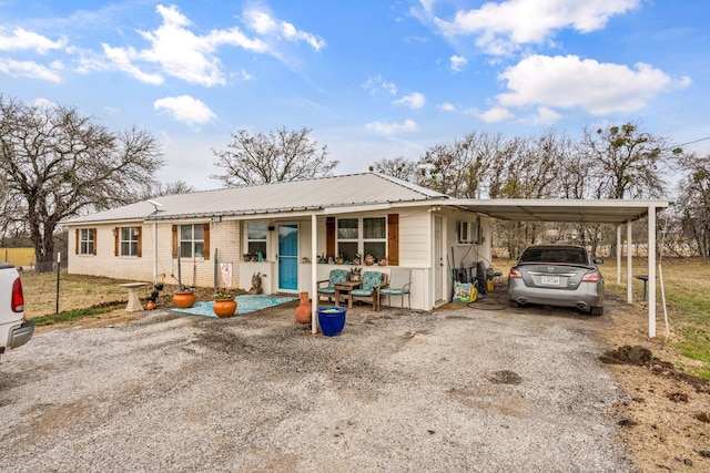 ranch-style home with gravel driveway, a carport, brick siding, and metal roof