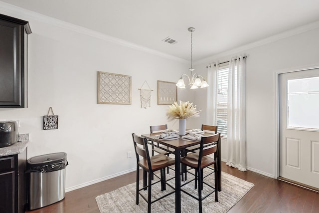 dining space featuring dark wood-style flooring, crown molding, visible vents, a chandelier, and baseboards