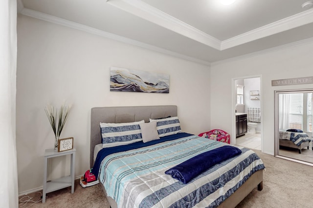 bedroom with connected bathroom, ornamental molding, a tray ceiling, and light colored carpet