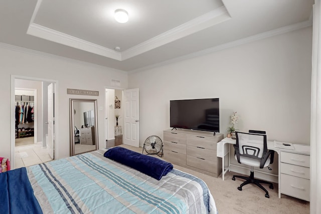 carpeted bedroom with a tray ceiling, a walk in closet, and ornamental molding