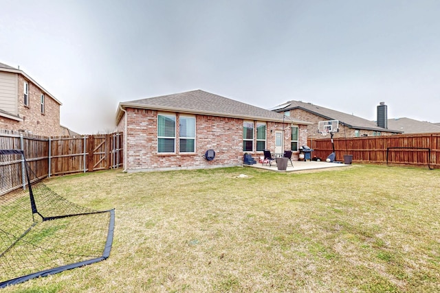 back of house with brick siding, a patio, a fenced backyard, and a lawn