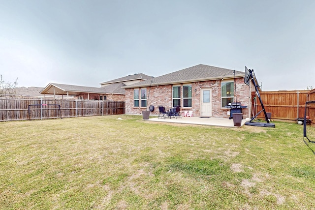 rear view of house with brick siding, a fenced backyard, a patio area, and a yard