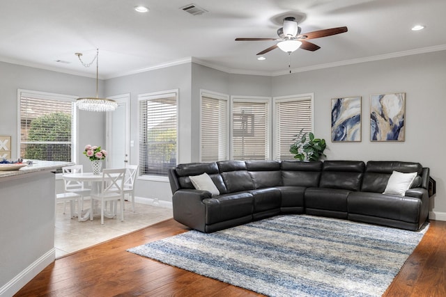 living room featuring wood-type flooring, visible vents, and crown molding